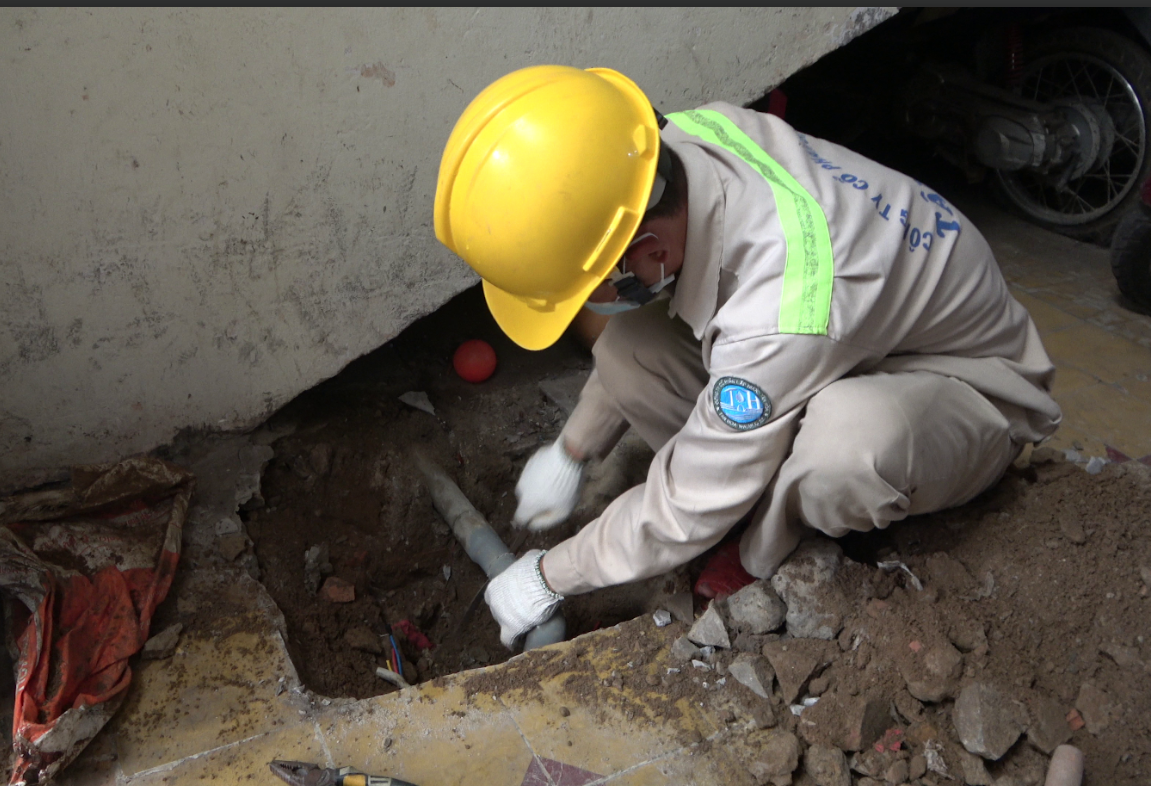 A person in a hard hat using a pipe  Description automatically generated