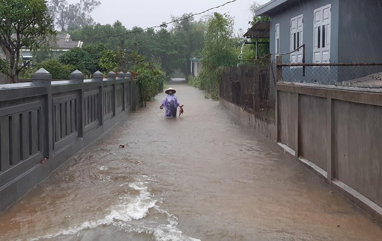 Một người dân đang lội nước trên đường làng do mưa lớn nhiều ngày tại thôn Xuân Tuý, xã Quảng Phú, huyện Quảng Điền, tỉnh Thừa Thiên - Huế. Ảnh: TTXVN/Mai Trang
